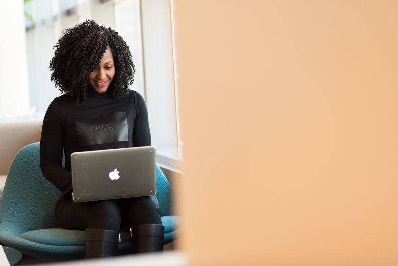 A woman smiling as she works on a MacBook